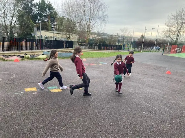 1st and 2nd Class pupils doing movement activities at stations in the school yard
