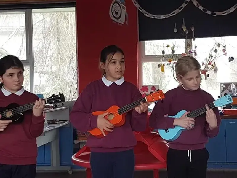 Pupils playing ukuleles in a classroom