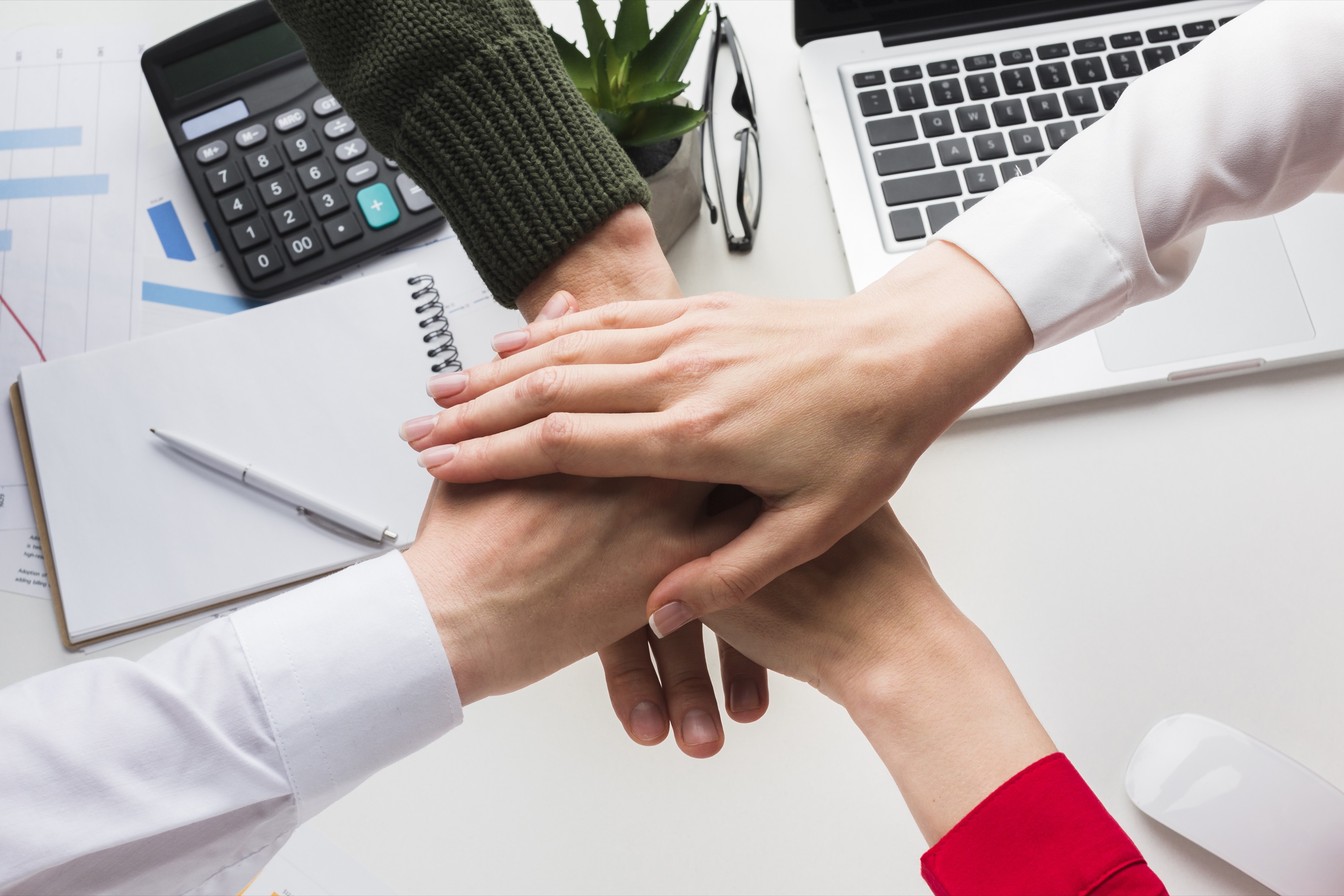 Mani di più persone unite una sopra l'altra su una scrivania di lavoro