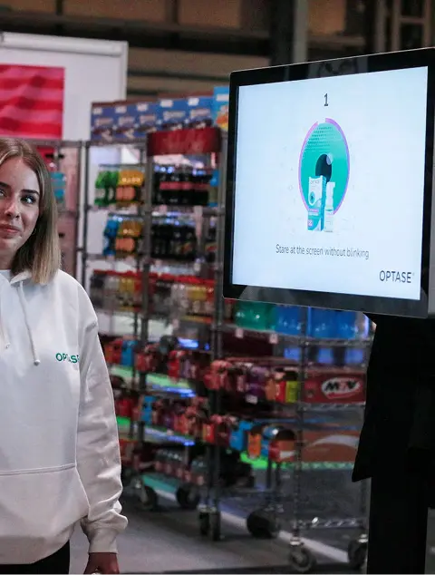Optase — person viewing branded screen in store (tall)