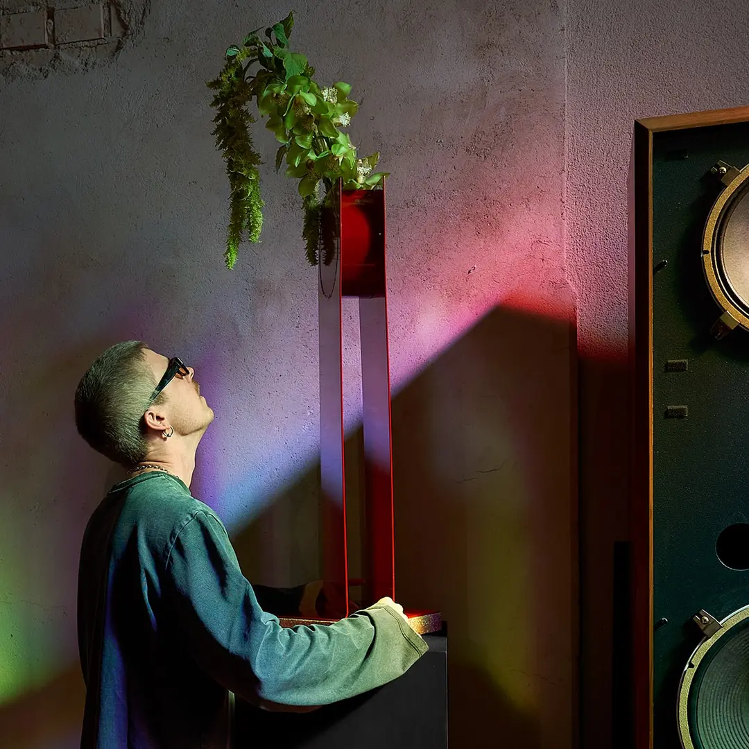 A man looking up at the Swish Vase in coloured light