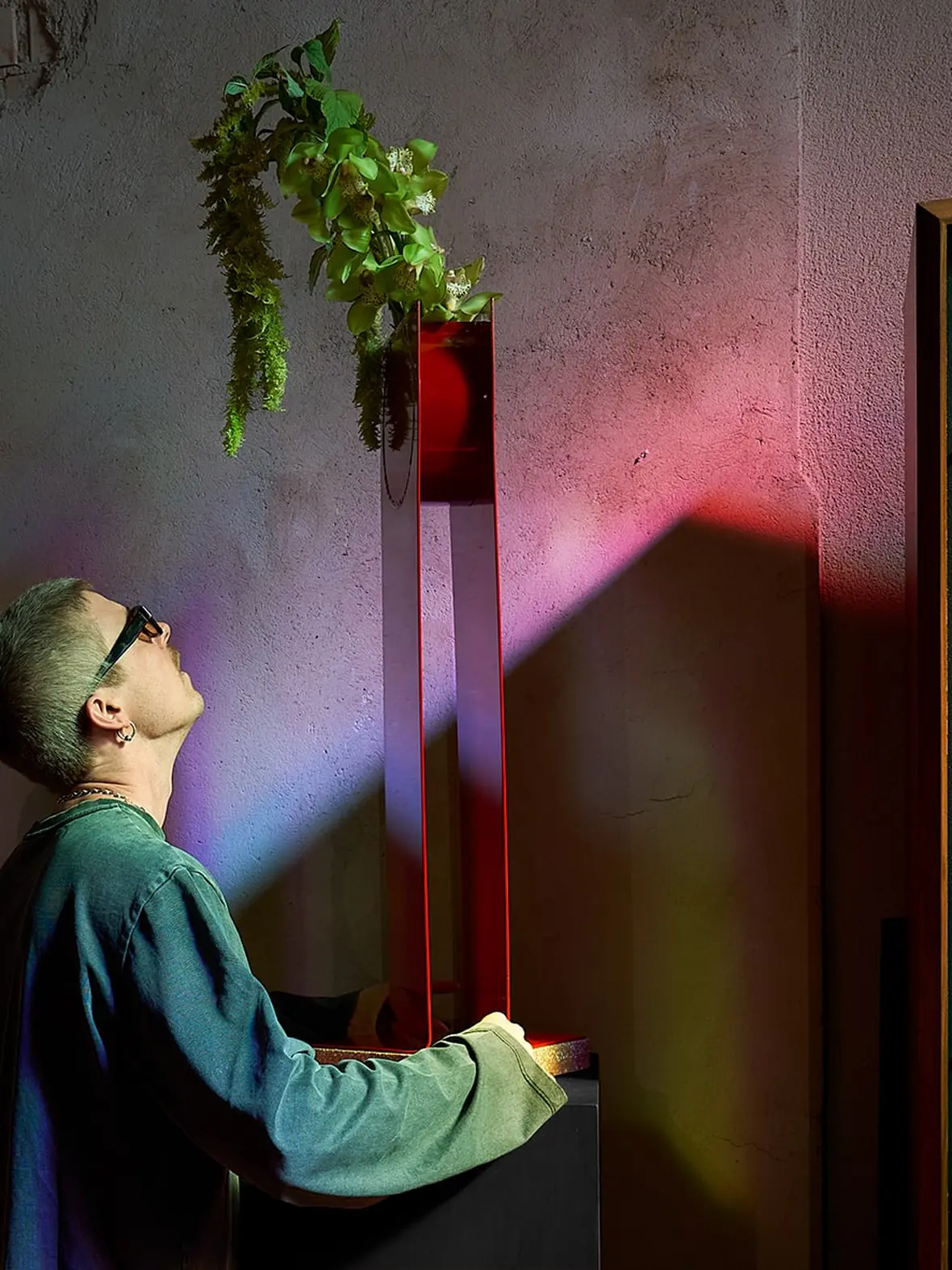A man looking up at the Swish Vase in coloured light