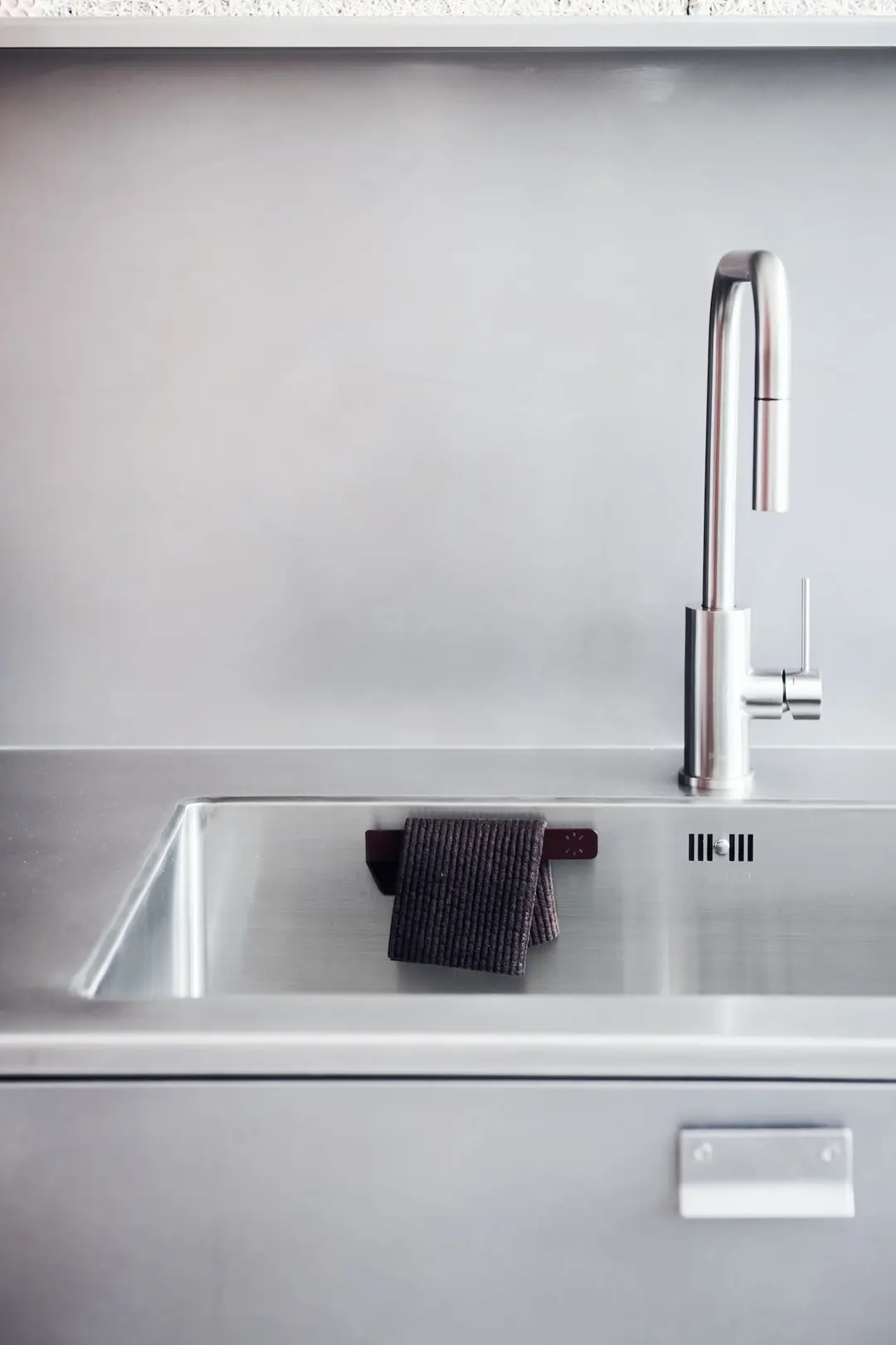 Dark dishcloth on the hanger in a stainless steel sink