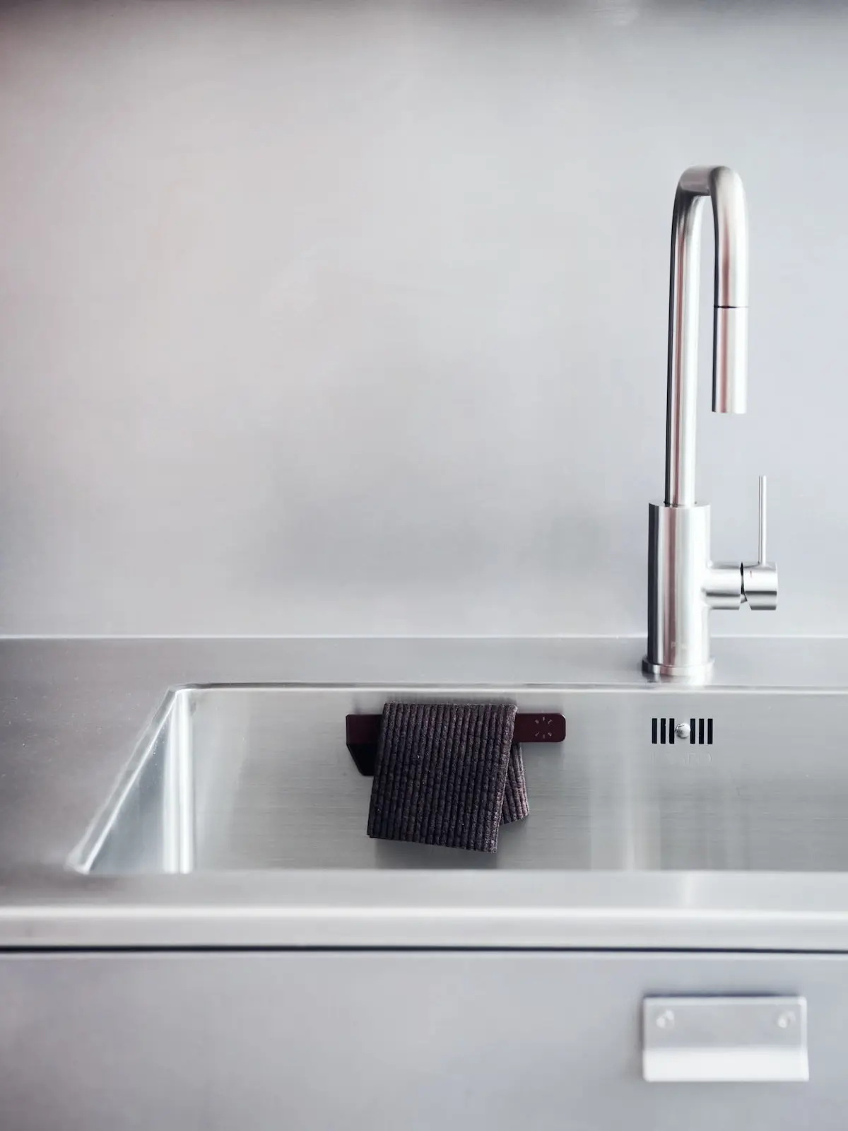 Dark dishcloth on the hanger in a stainless steel sink
