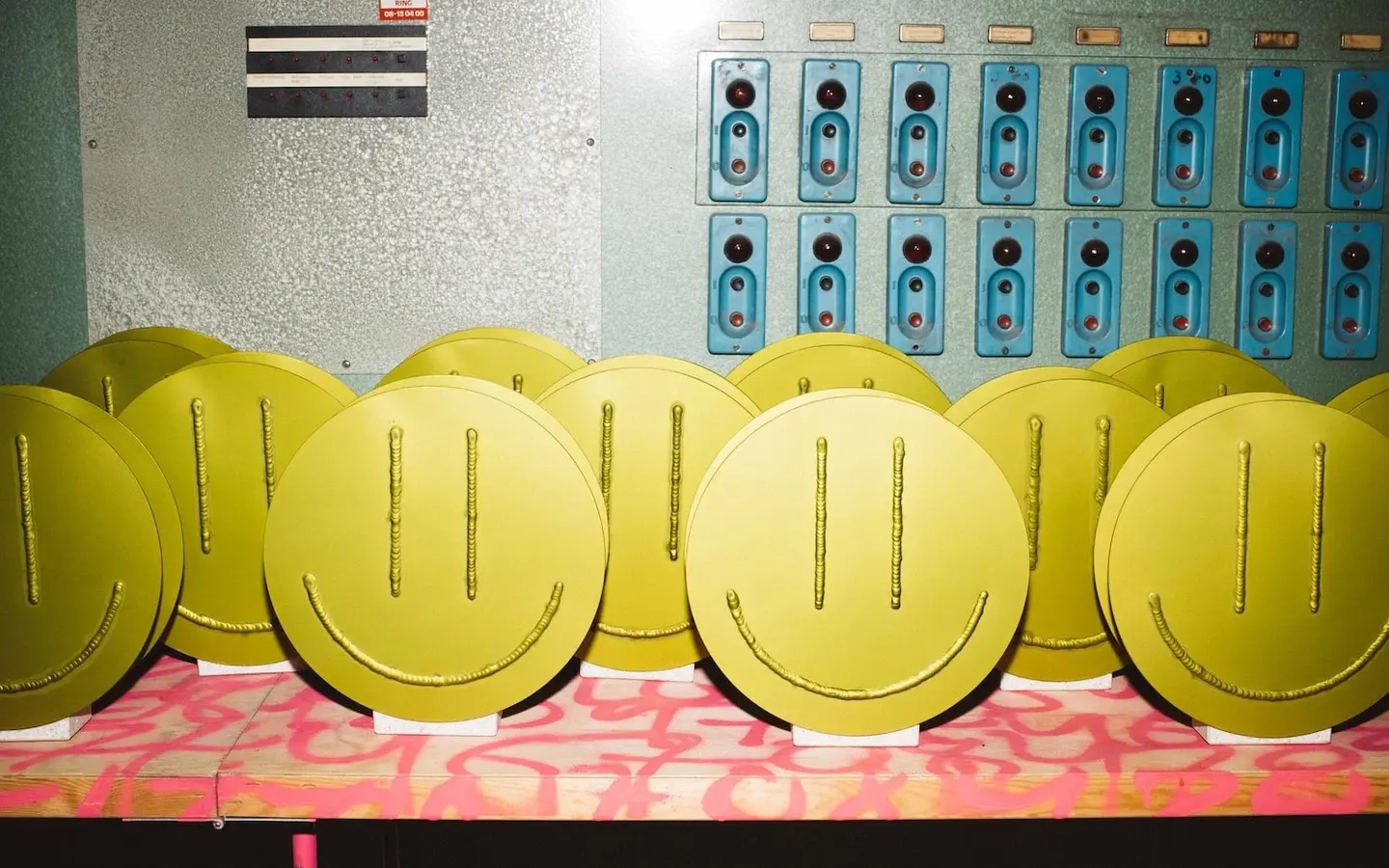 A row of yellow Acid Vases in front of a control panel