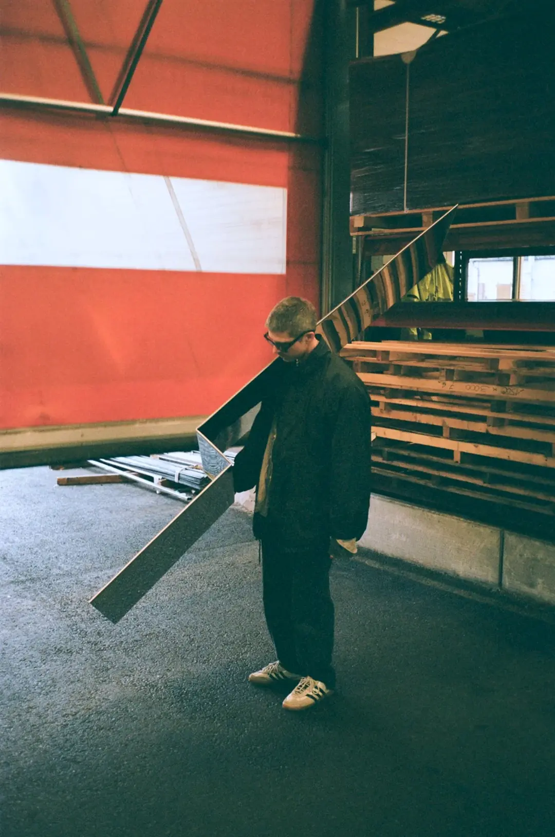 A person carrying a long sheet of steel in a workshop