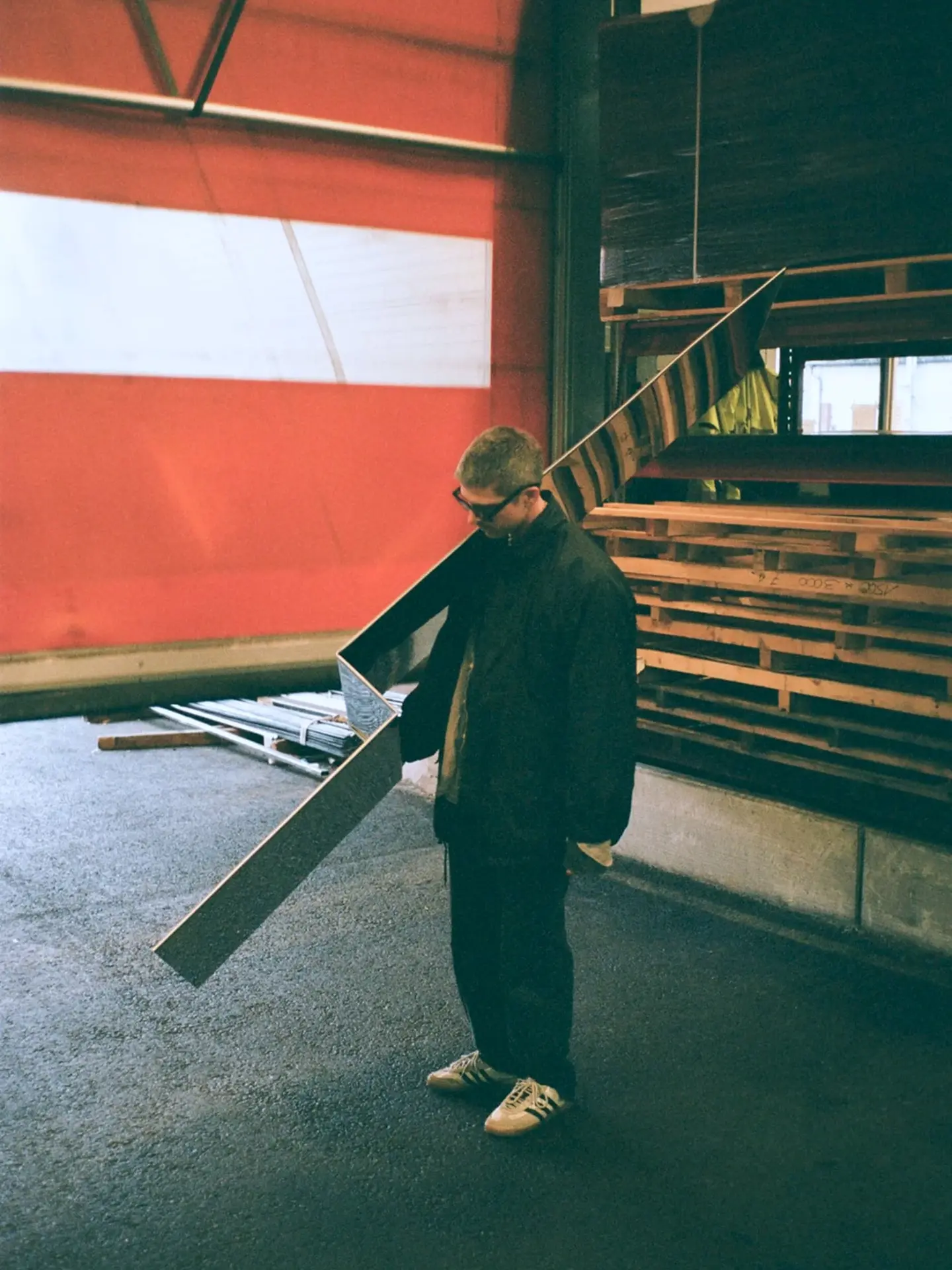 A person carrying a long sheet of steel in a workshop