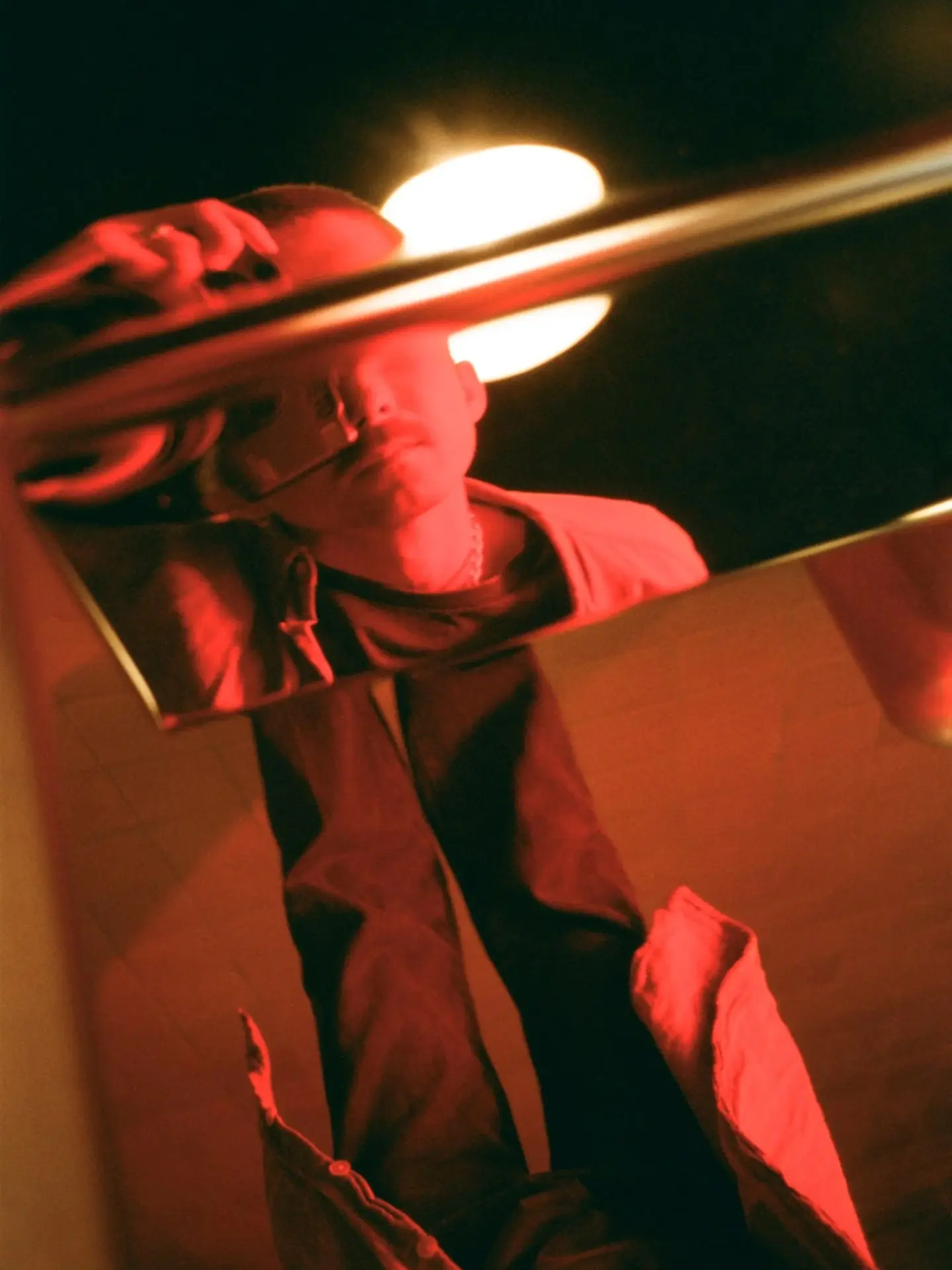 Face reflected in polished steel under red light