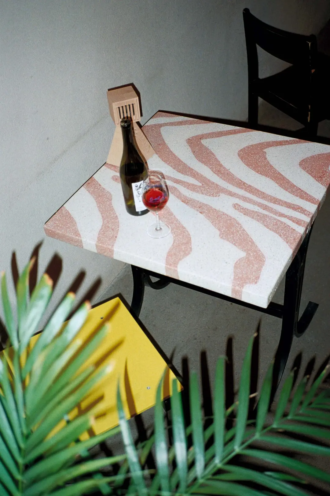 Pink and white terrazzo table with a wine bottle and a glass