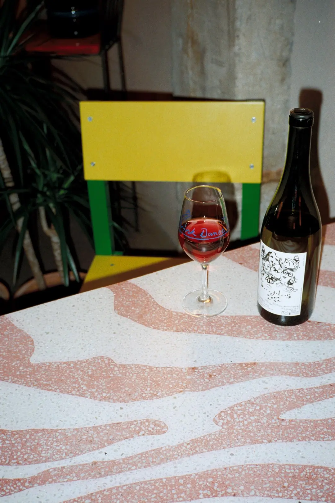 Glass of wine and a bottle on a pink terrazzo table