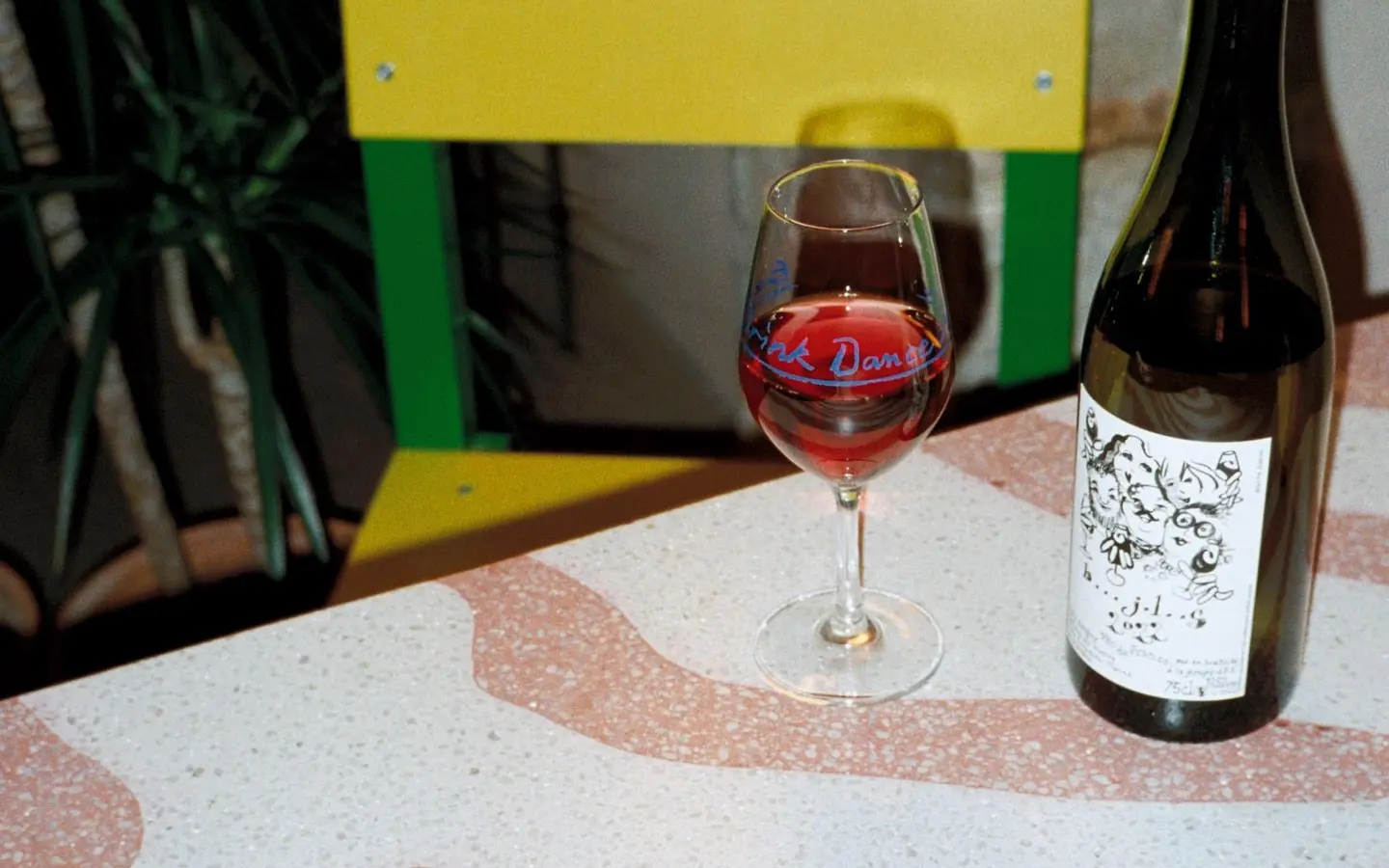 Glass of wine and a bottle on a pink terrazzo table