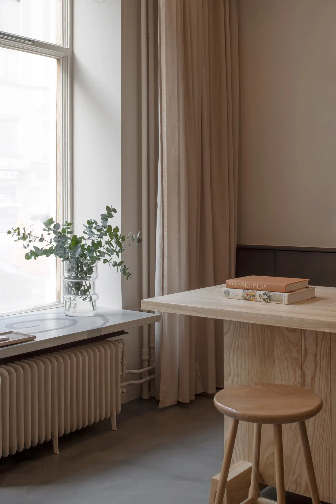 Wooden table and stool by a tall window