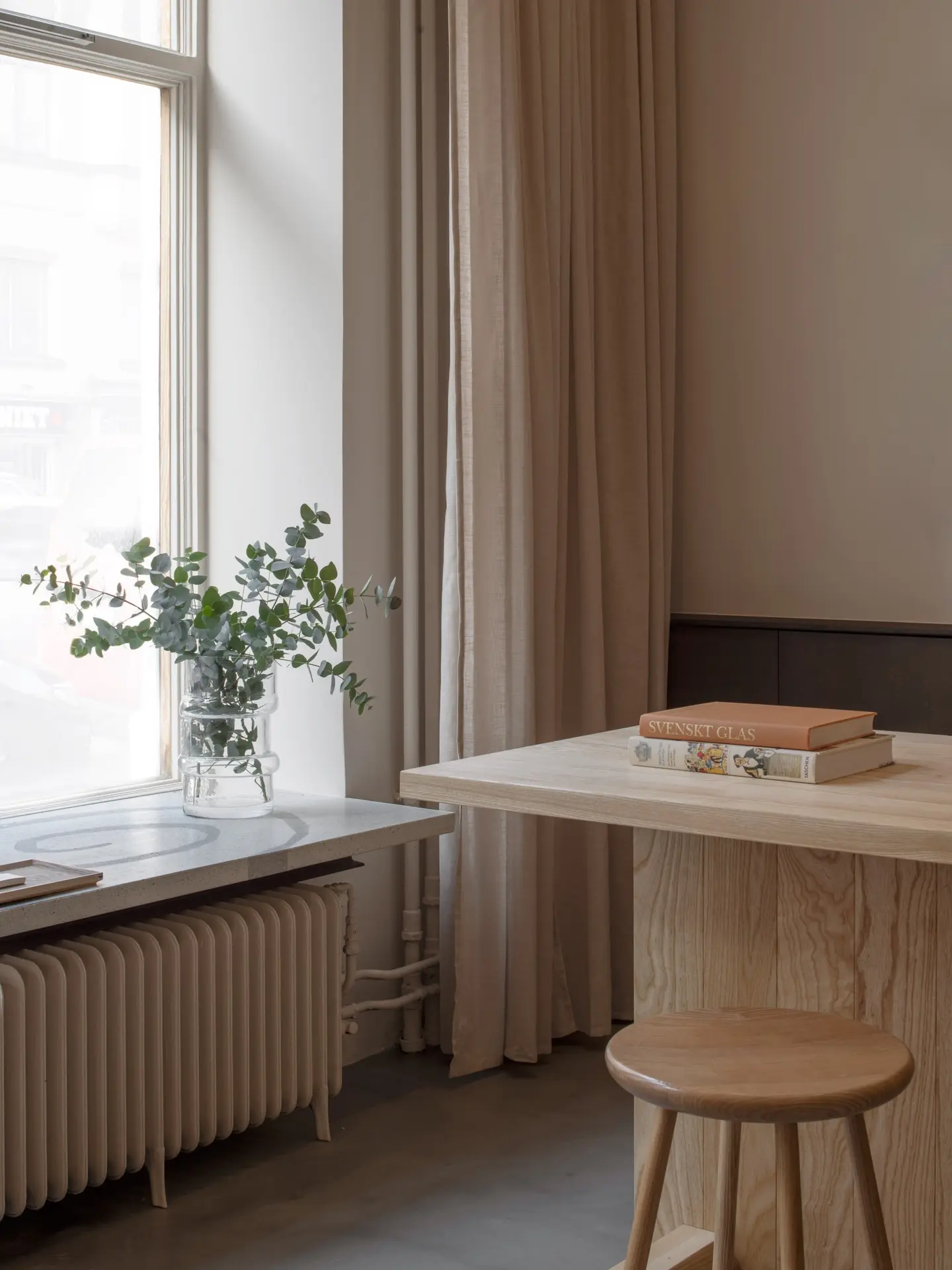 Wooden table and stool by a tall window