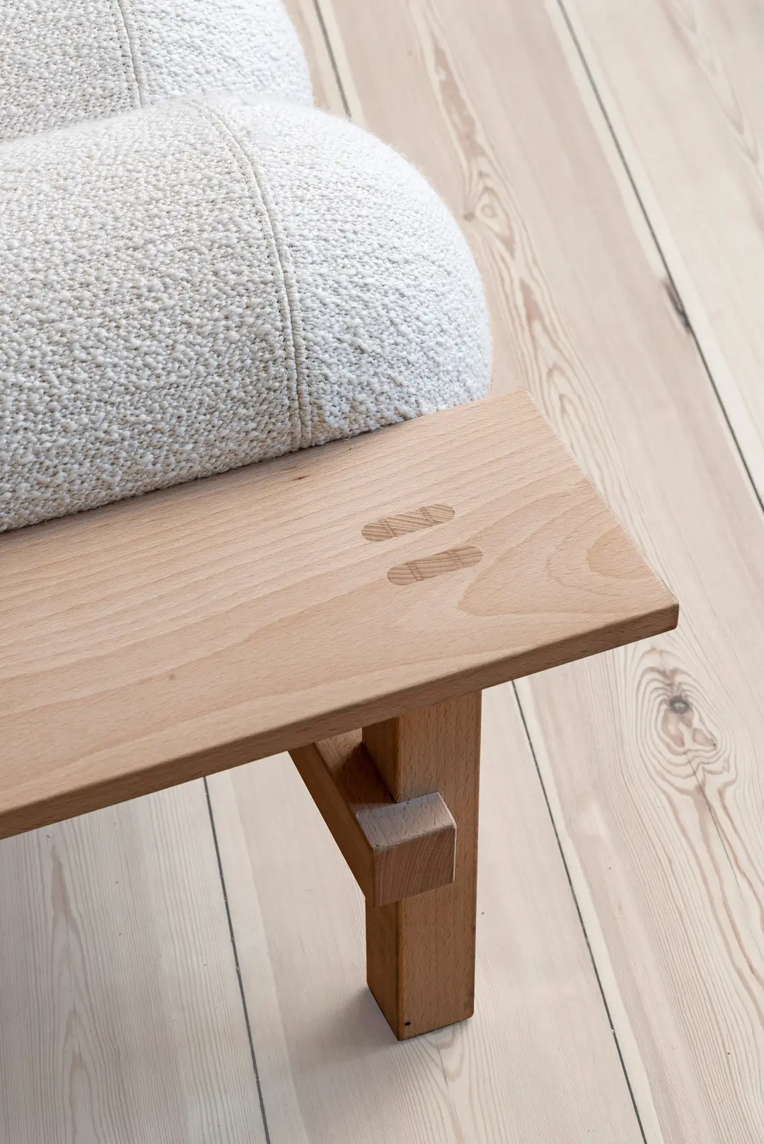 Close-up of the beech frame joint below a white bouclé cushion