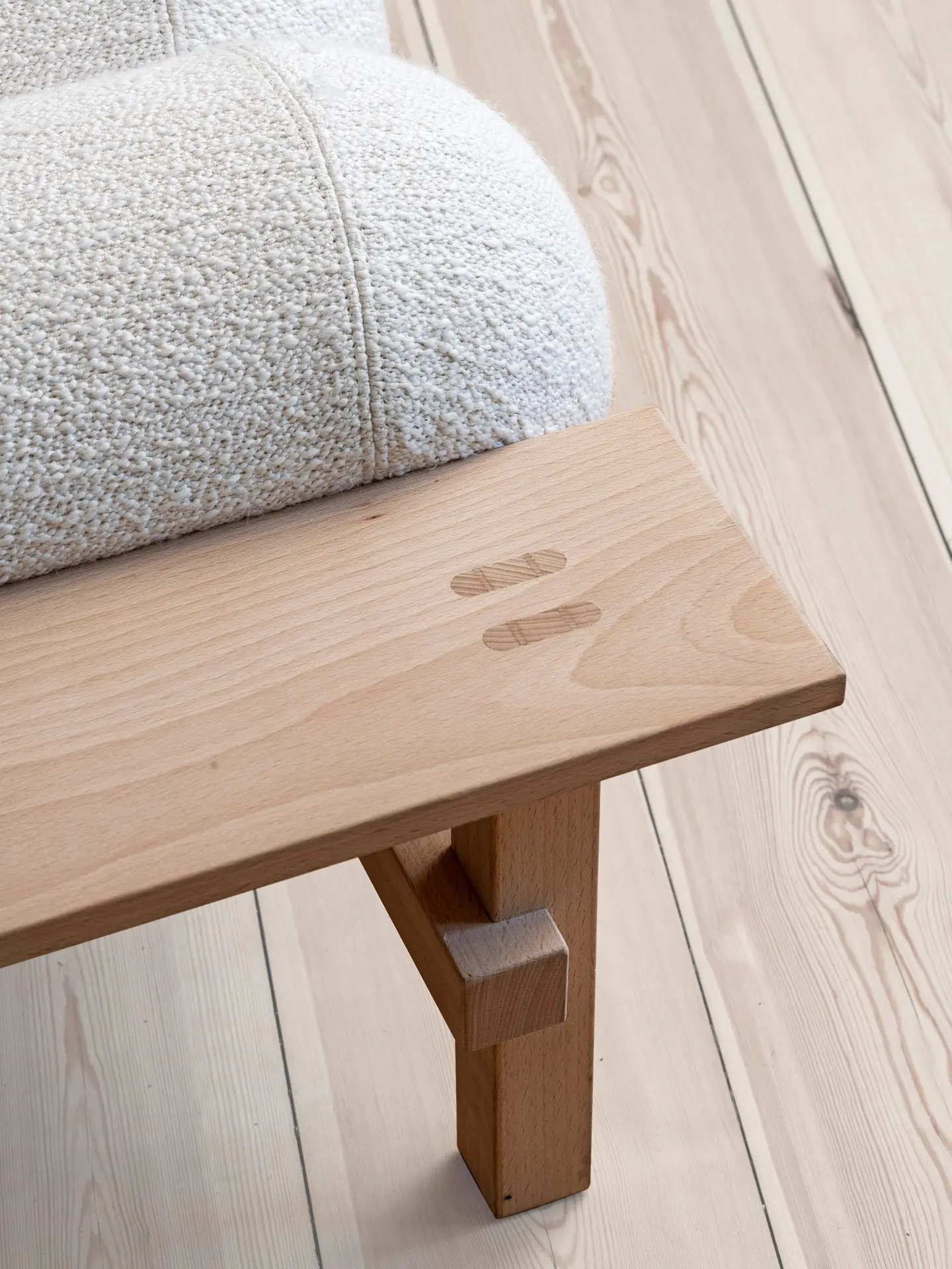 Close-up of the beech frame joint below a white bouclé cushion