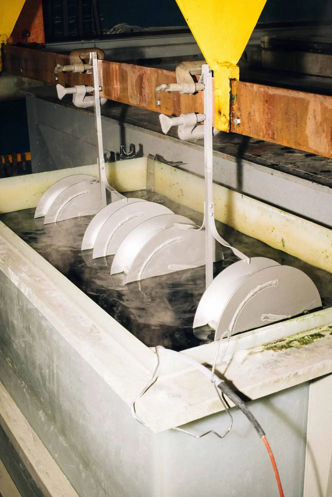 Vases hanging in an anodising bath in the factory