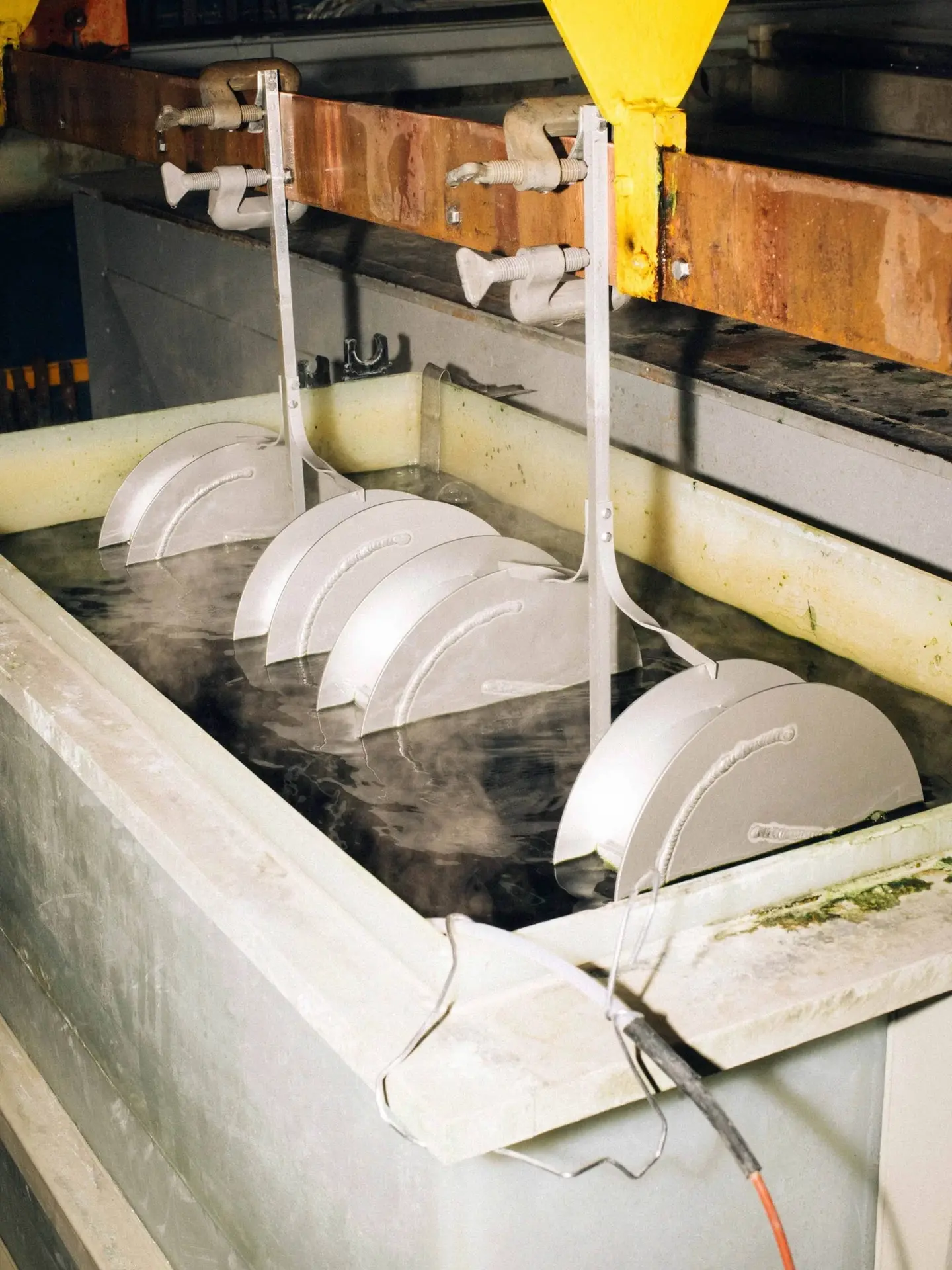 Vases hanging in an anodising bath in the factory