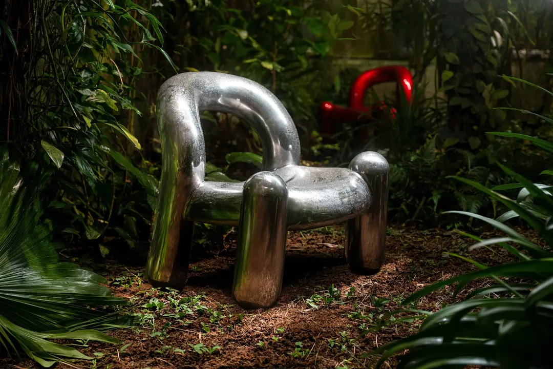 Silver Reality chair in the greenery with a red one behind it