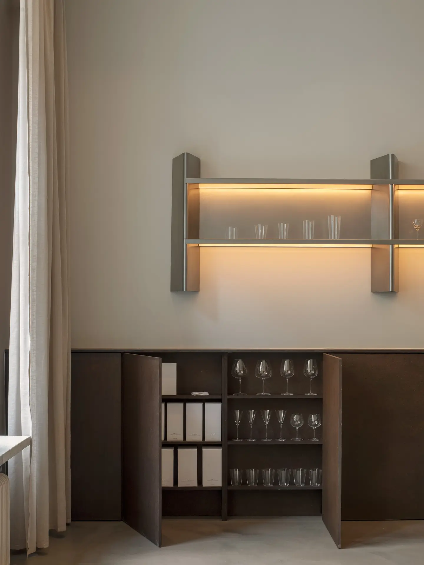 Lit steel shelf above a cabinet with glassware