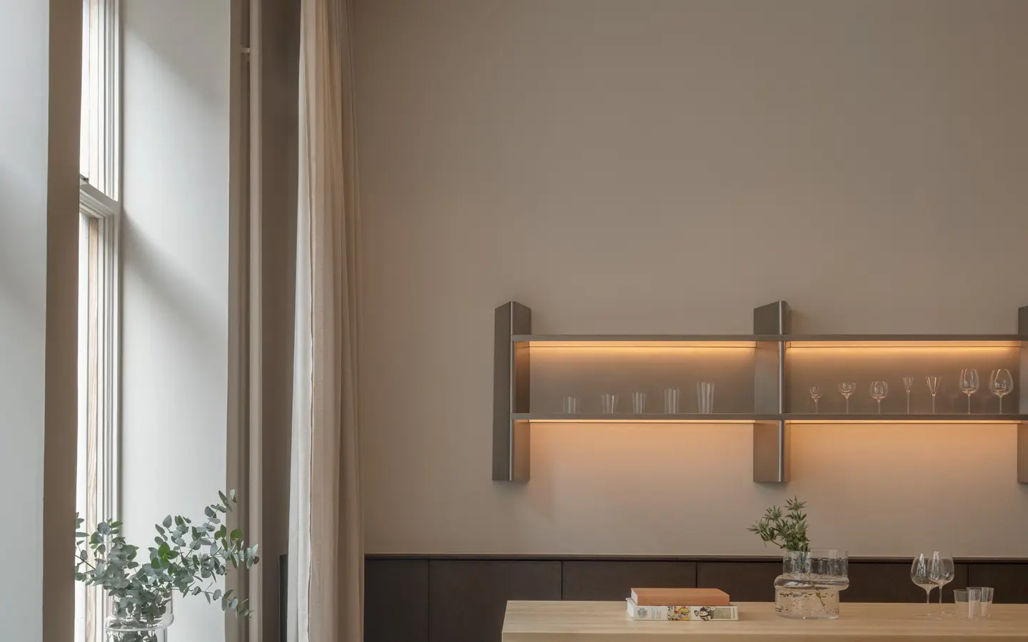 BOBO showroom with a pale wooden table, stools and a lit shelf