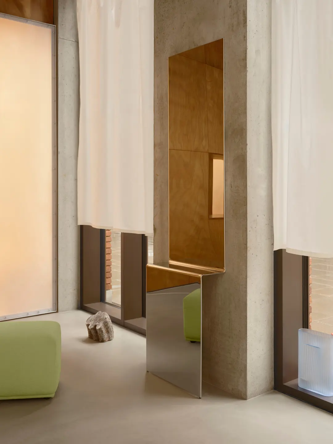 Pleat mirror against a concrete pillar between pale curtains