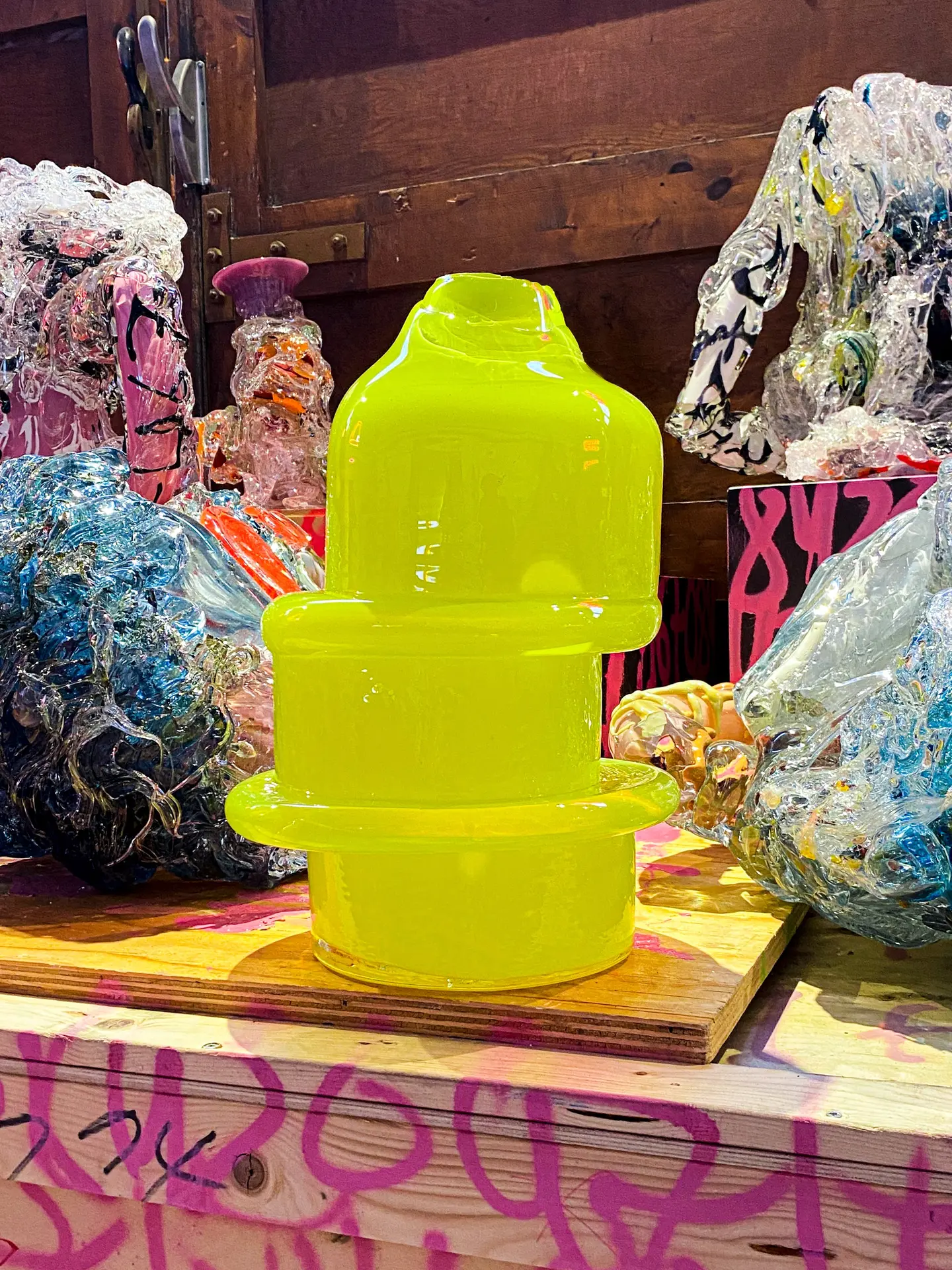 Yellow Skew sculpture among glass objects on a painted table