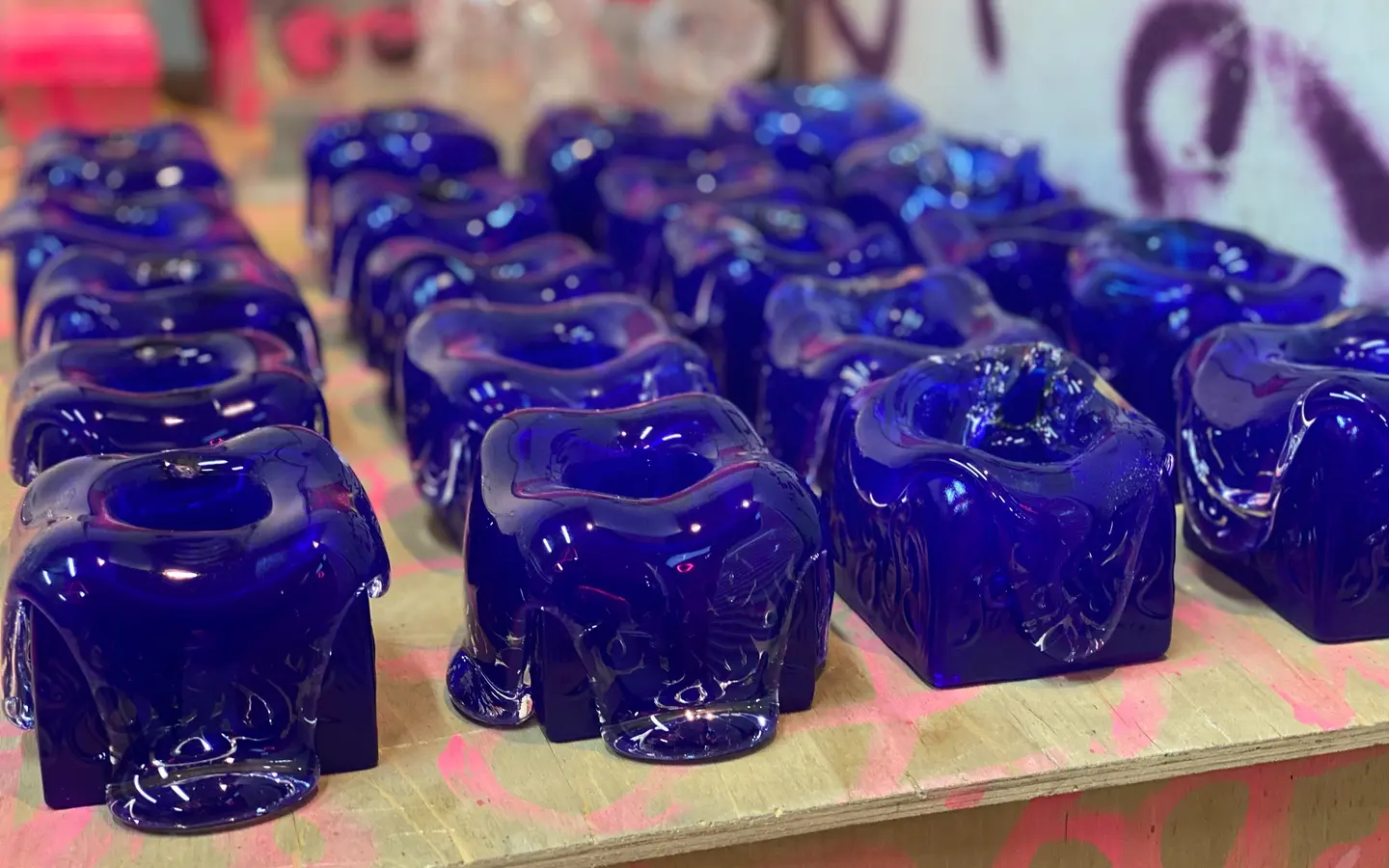 Rows of blue Syrup candleholders on a graffiti table