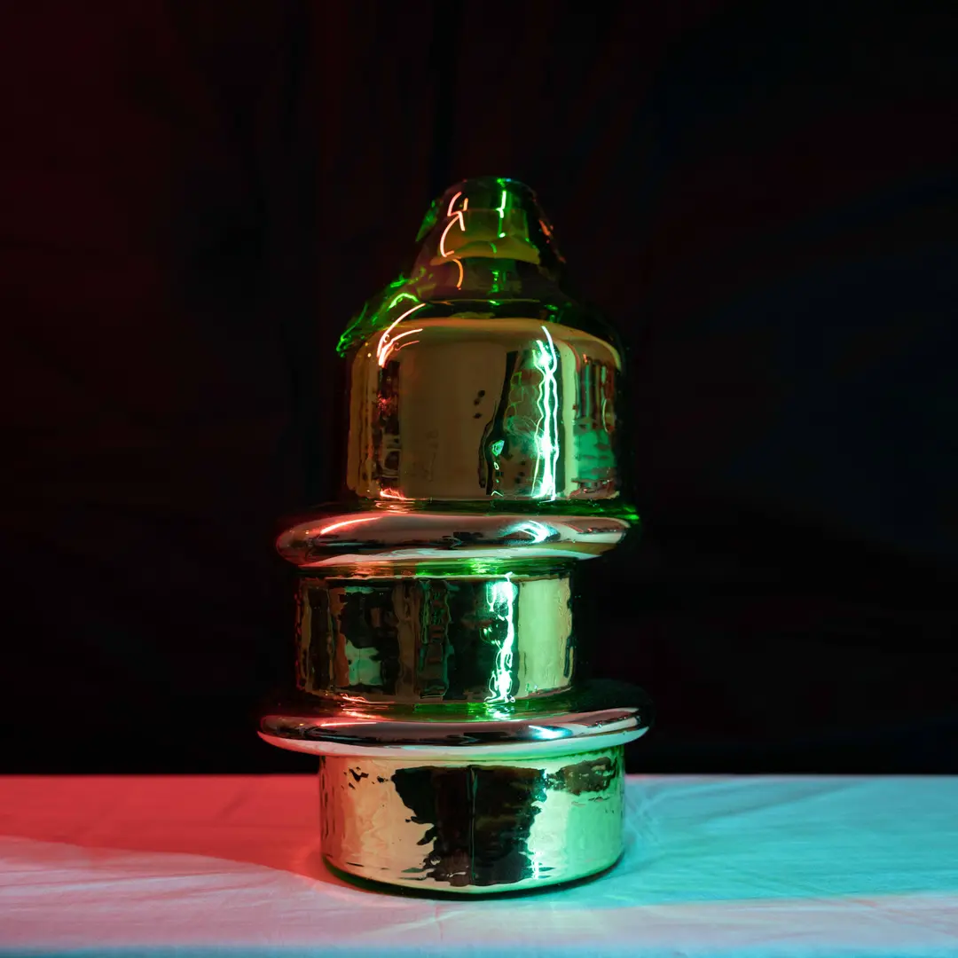 Mirrored green Skew sculpture under coloured light