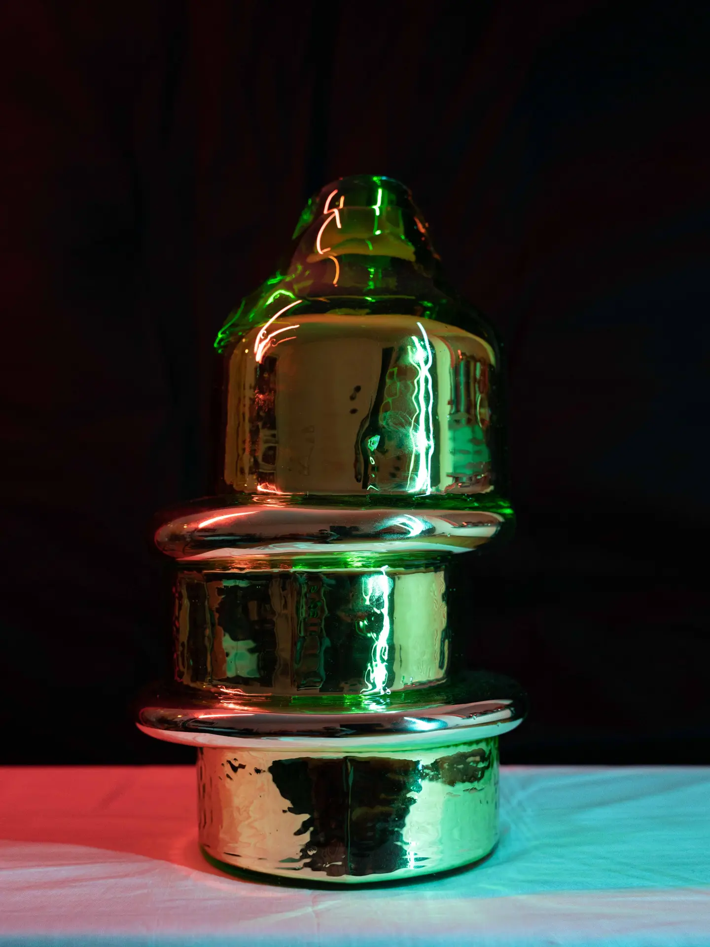 Mirrored green Skew sculpture under coloured light