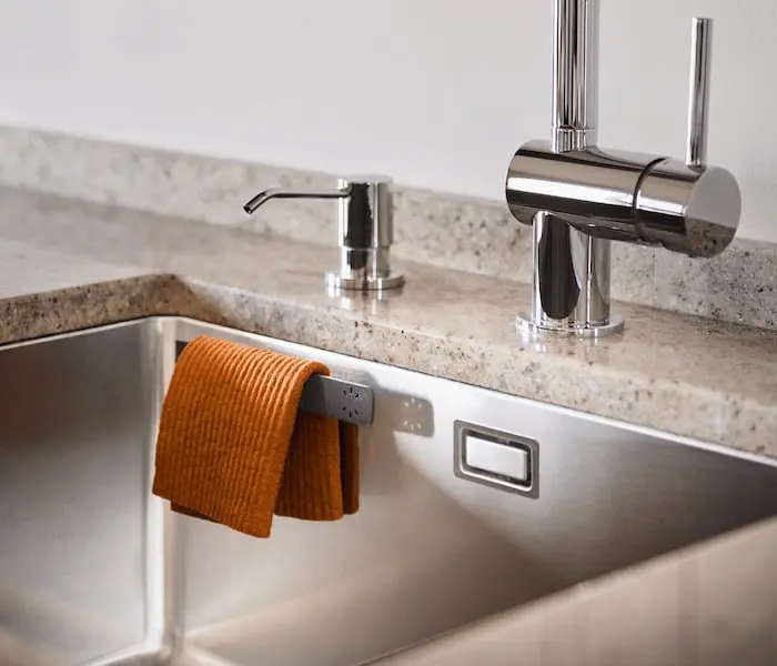 Orange dishcloth on the hanger in a steel kitchen sink