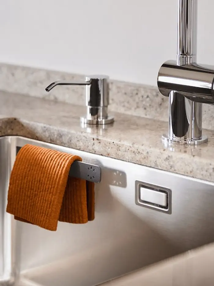 Orange dishcloth on the hanger in a steel kitchen sink