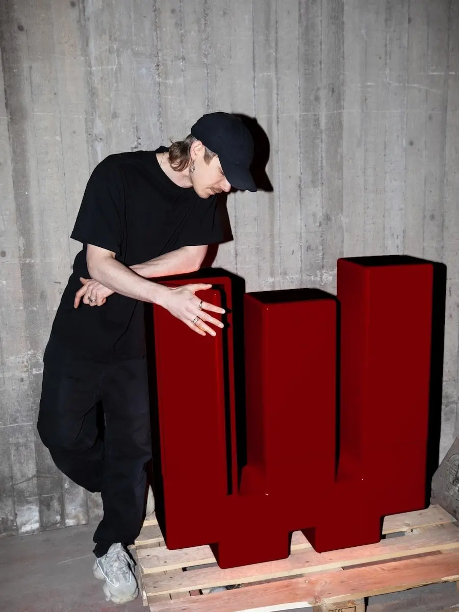 Gustav Winsth leaning on the red Inferno cabinet on a pallet