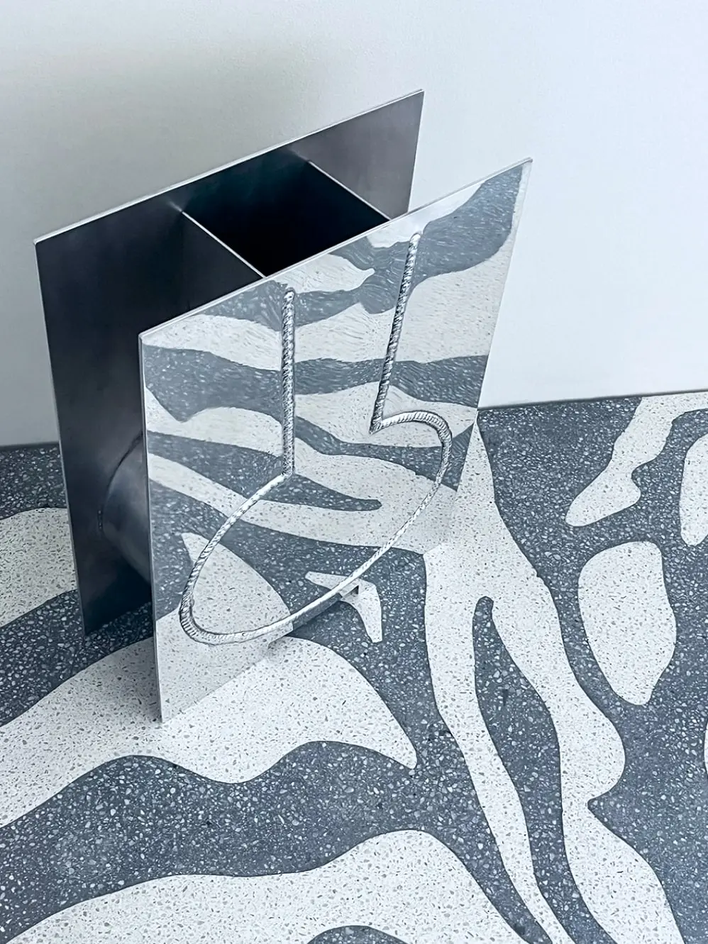 TIG_002 in mirror-polished steel on a patterned terrazzo floor