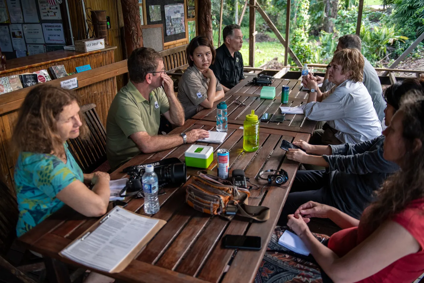 People seated around a table at a meeting, taking notes