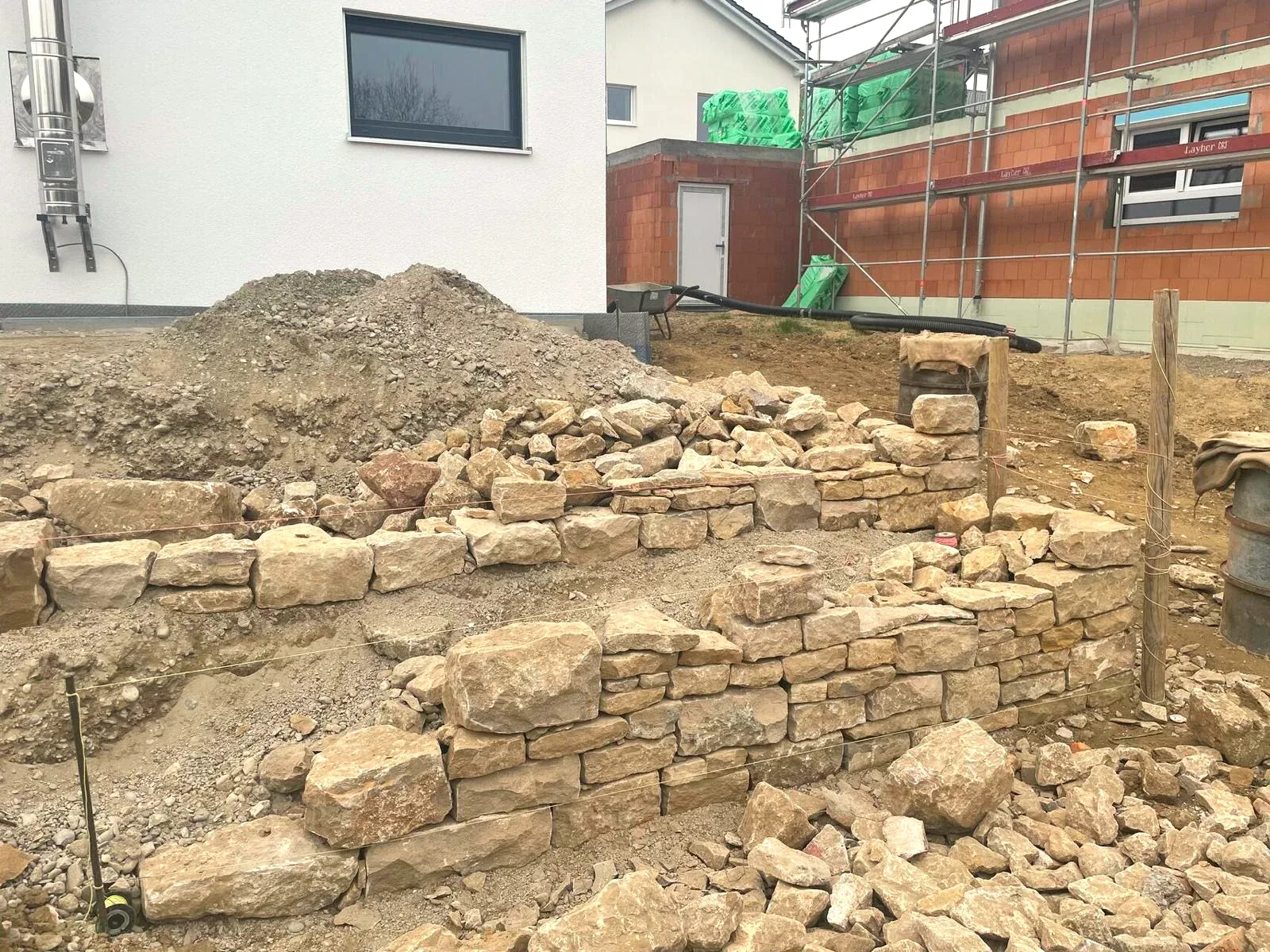 Aufbau einer Natursteinmauer mit unterschiedlich großen Steinen vor dem Wohnhaus