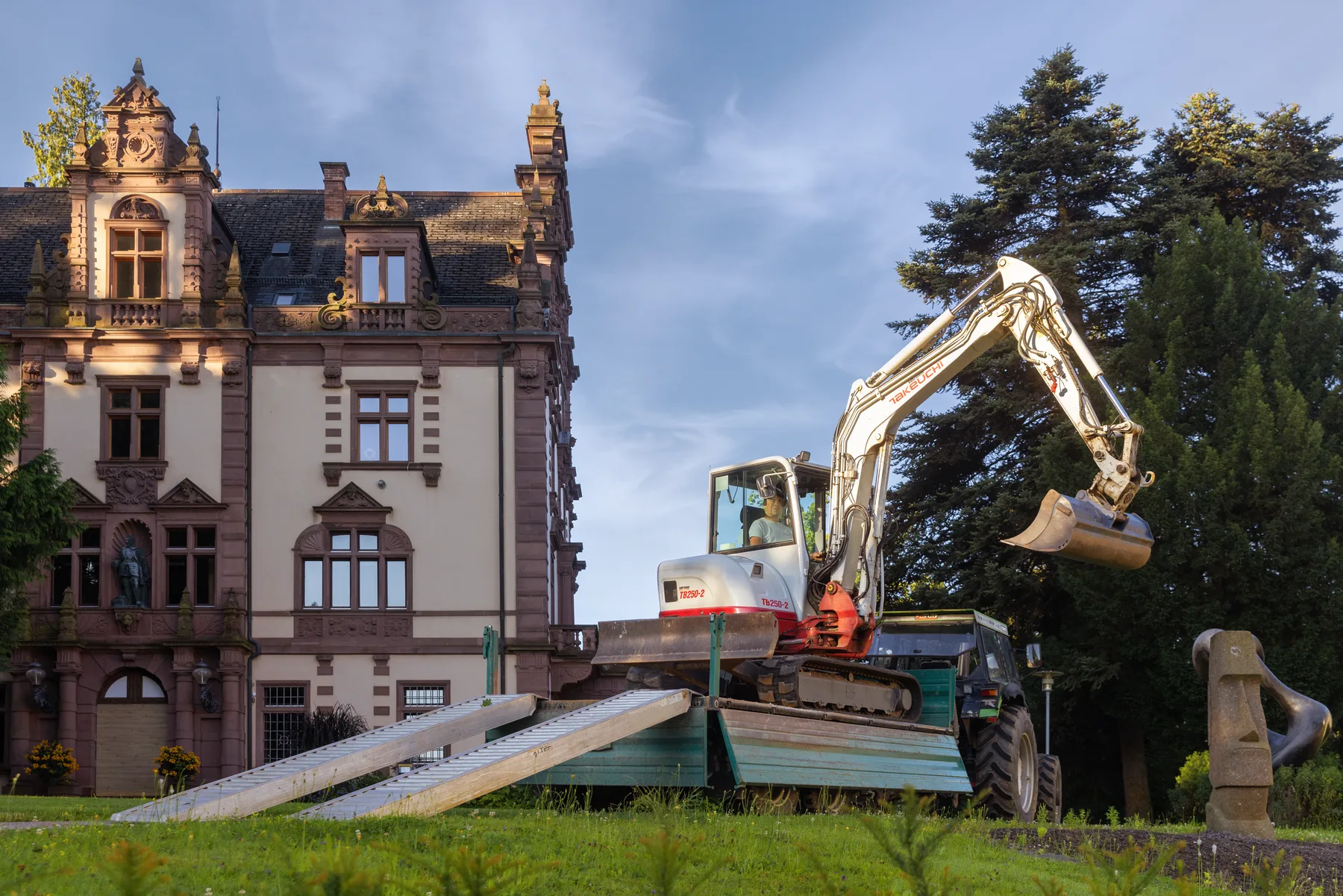 Mitarbeiter bringt einen Bagger zu einer Gartenbaustelle
