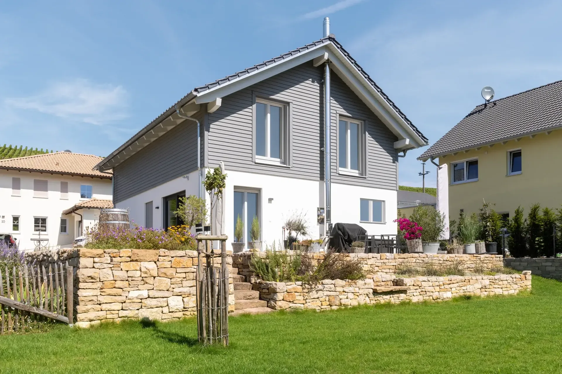 Natursteinmauer an einem Wohnhaus mit gestaffelten Pflanzflächen