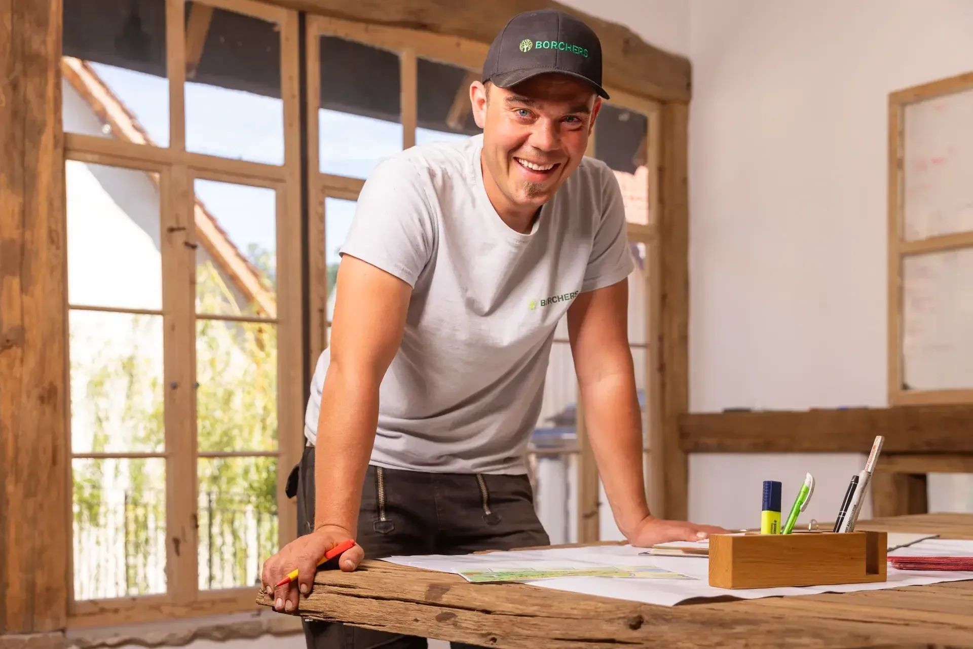 Andreas Borchers an einem Holztisch mit Gartenplänen