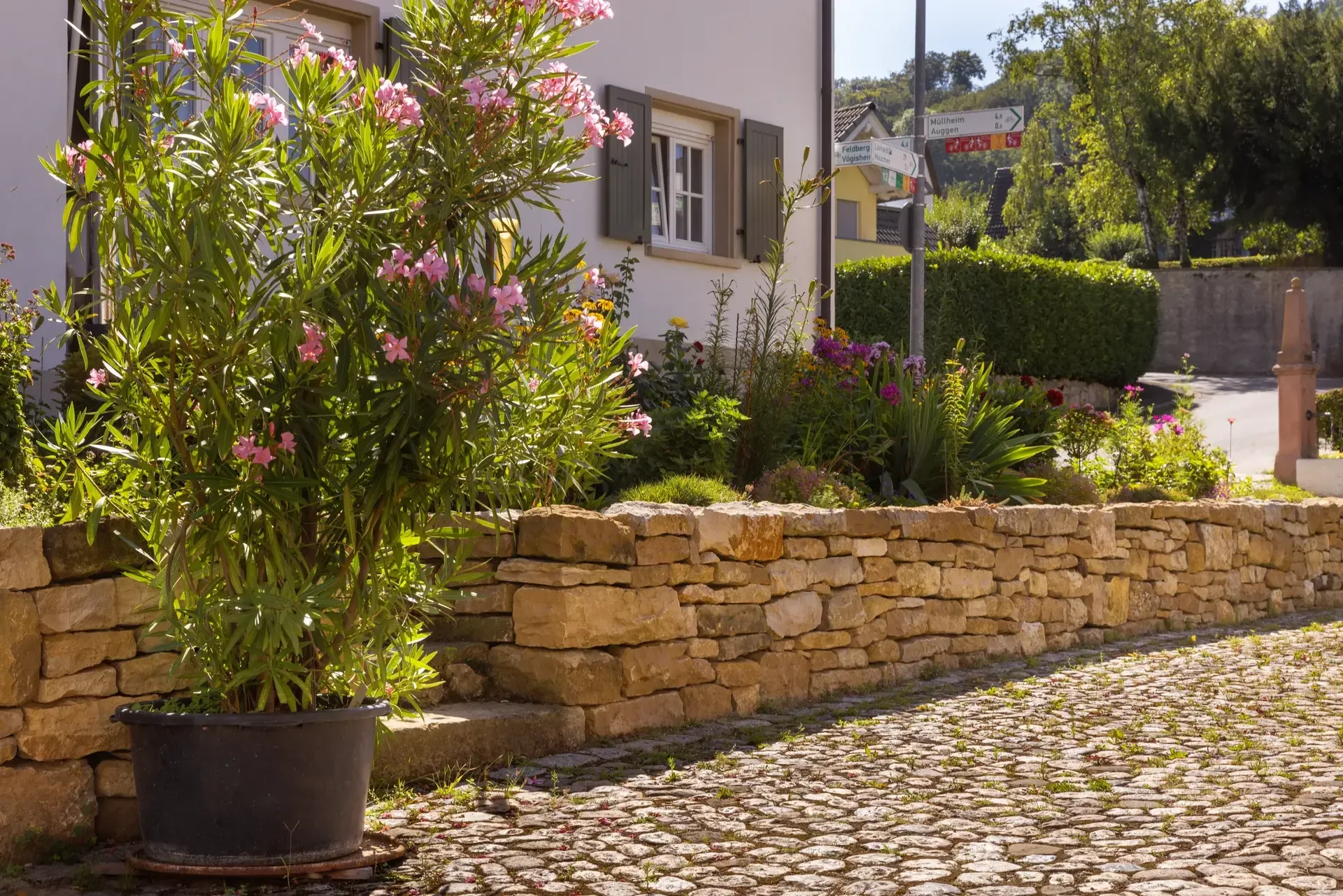 Fertiger Bauerngarten mit blühender Bepflanzung und Naturstein-Trockenmauer am Hof