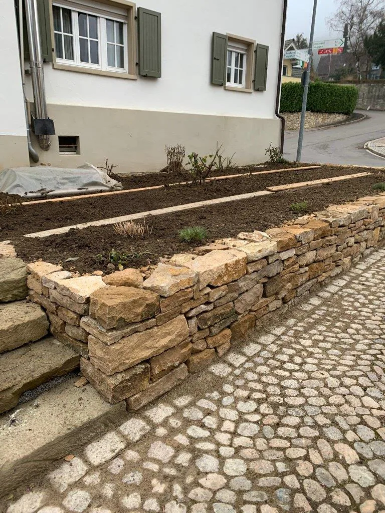 Bau einer Trockenmauer aus Naturstein in einem Bauerngarten