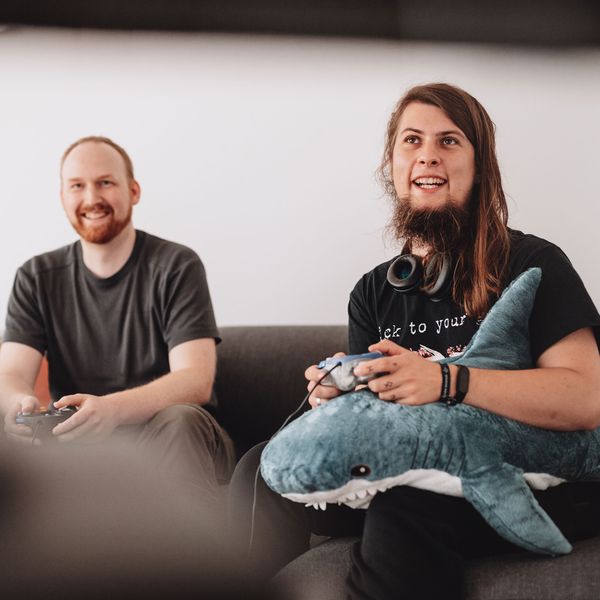 Zwei Männer sitzen auf einem Sofa und spielen ein Computerspiel