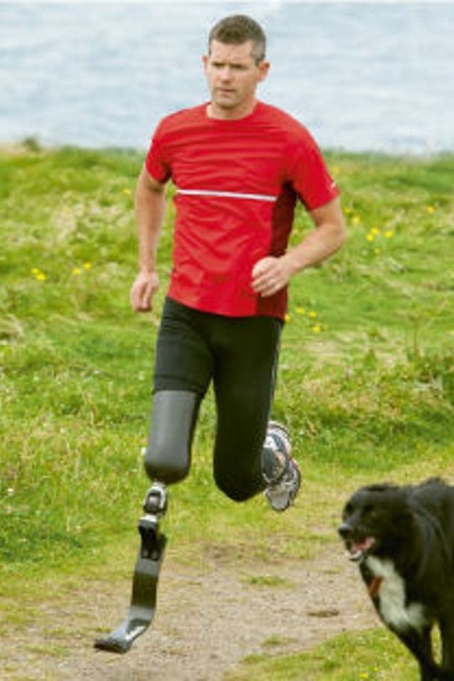 Ein Mann mit einer Beinprothese joggt mit einem Hund
