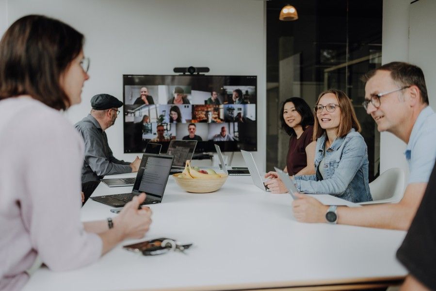 Mitarbeiter sitzen im Büro und remote zusammen