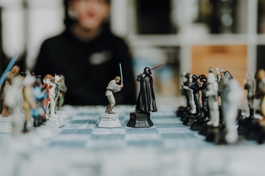 Ein Star Wars Schachspiel, im Hintergrund sieht ein junger Mann dem Spiel zu