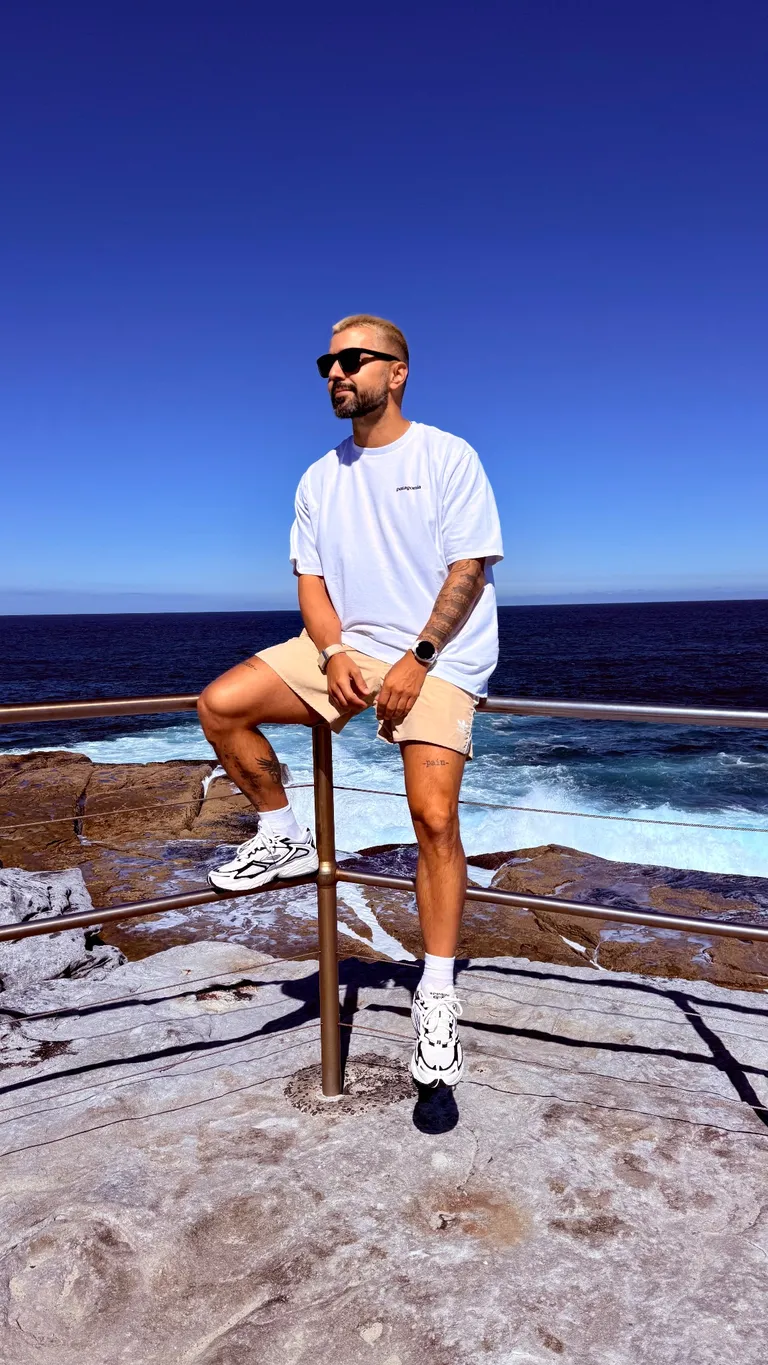 Serkan stands by a railing above a rocky coastline overlooking the sea.