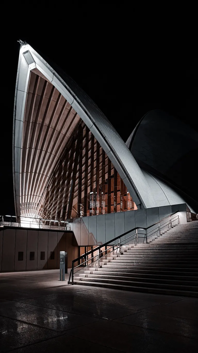 The illuminated roofs and steps of the Sydney Opera House at night.