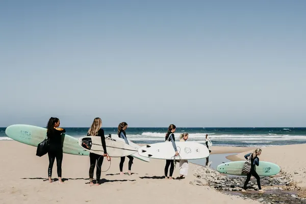 A group of women carrying surfboards on the beach
