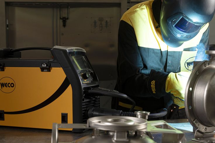 Operatore in abbigliamento protettivo che salda un componente metallico con una saldatrice WECO Micropulse 225 in ambiente industriale alla fiera Blechexpo