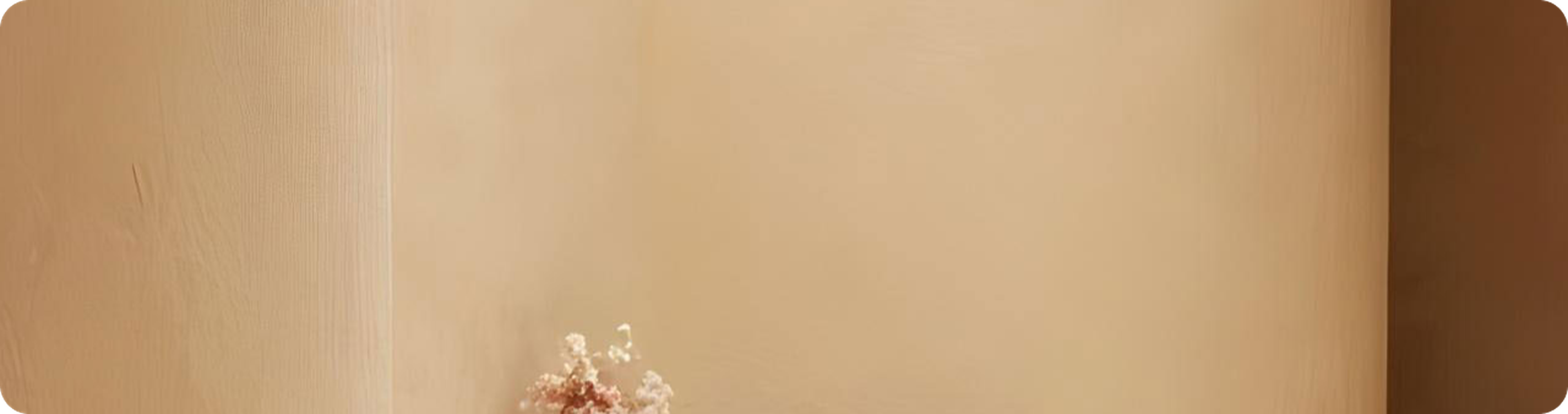 Minimalist beige background with a small bouquet of delicate dried flowers in the bottom left corner.