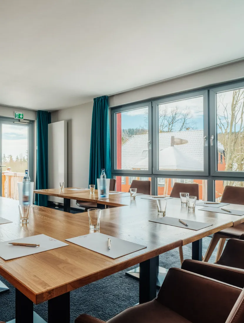 Moderner Tagungsraum im Harz mit großen Fenstern, Blick ins Grüne und Konferenztisch